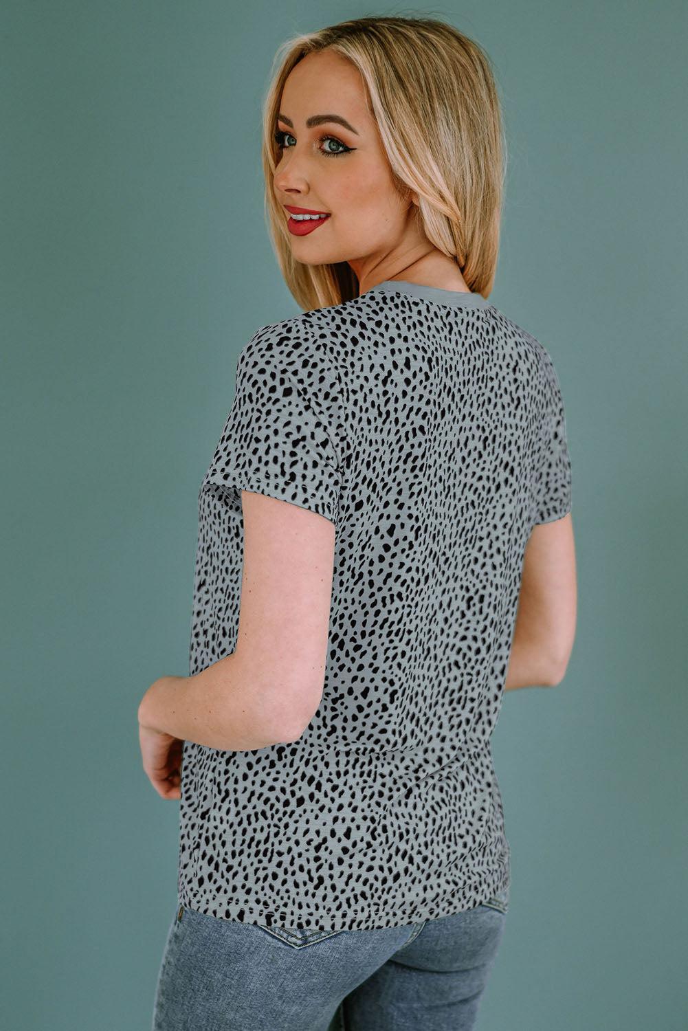 a woman wearing a black and white top with a leopard print