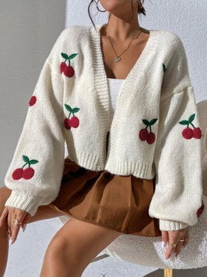 a woman sitting on a chair wearing a white sweater with cherries on it