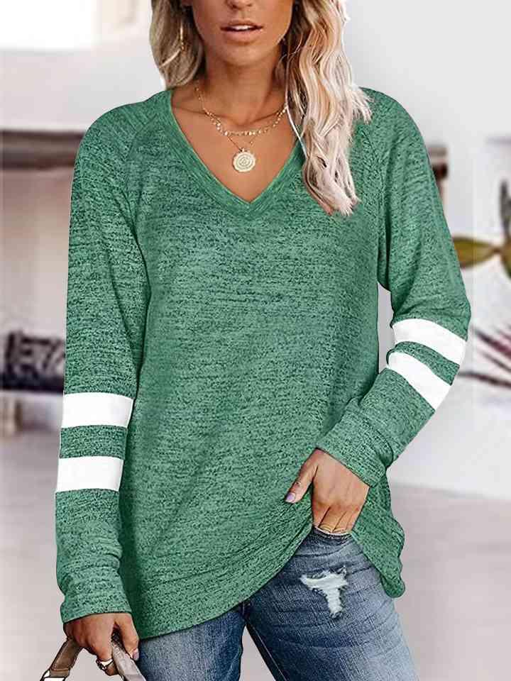 a woman wearing a green sweater and ripped jeans