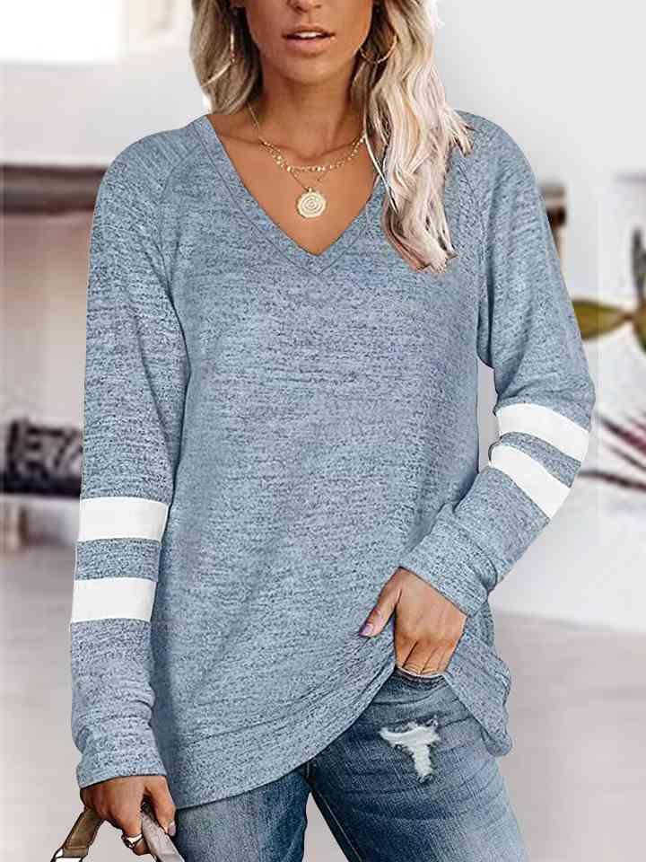 a woman wearing a blue sweater and ripped jeans