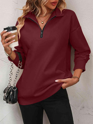 a woman holding a cup of coffee and wearing a red shirt