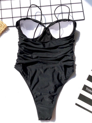 a black one piece swimsuit laying on top of a table