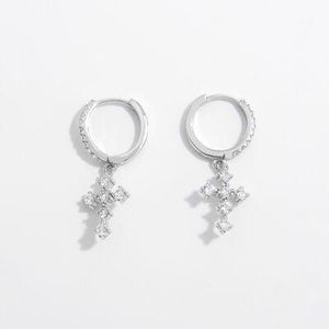 a pair of silver earrings with a cross on each ear