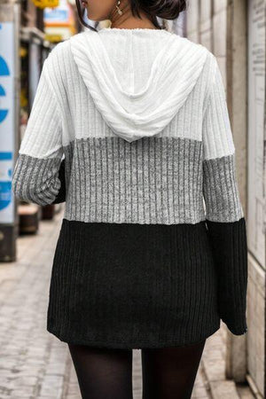 a woman walking down a street wearing a sweater