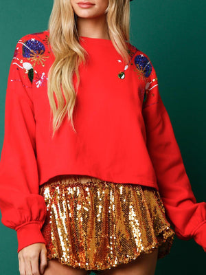 a woman wearing a red top and gold sequin skirt