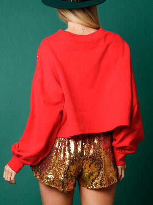 a woman in a red top and gold shorts
