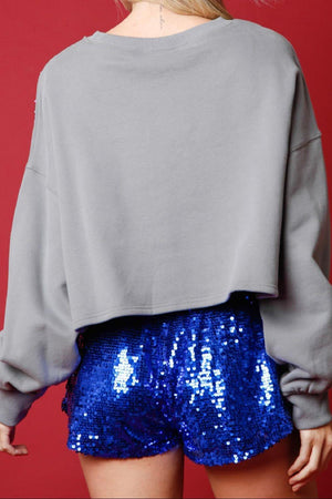 a woman wearing a blue sequin shorts and a grey sweatshirt