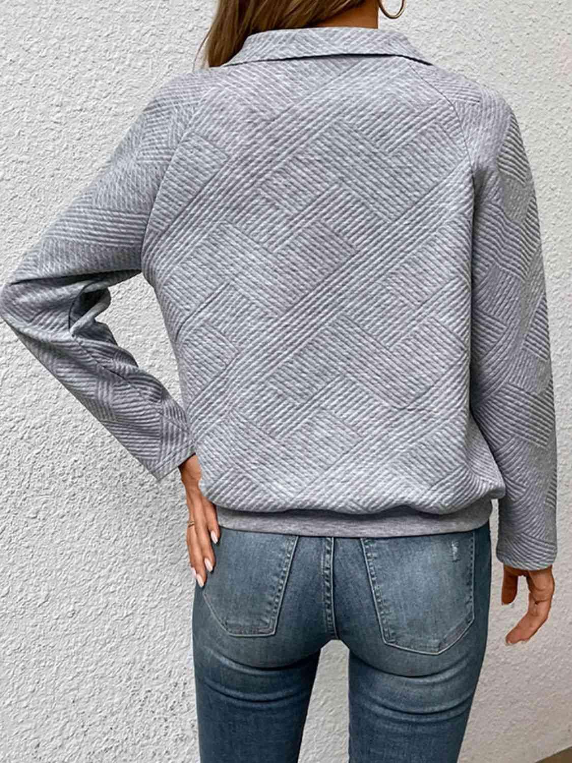 a woman wearing a grey sweater and jeans