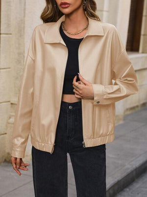 a woman standing on a sidewalk wearing a tan jacket