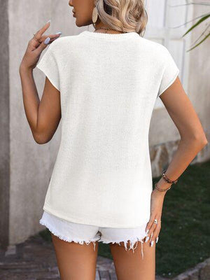 a woman wearing a white top and white shorts