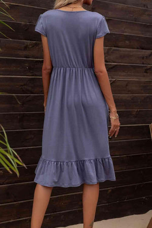 a woman in a blue dress standing in front of a wooden wall