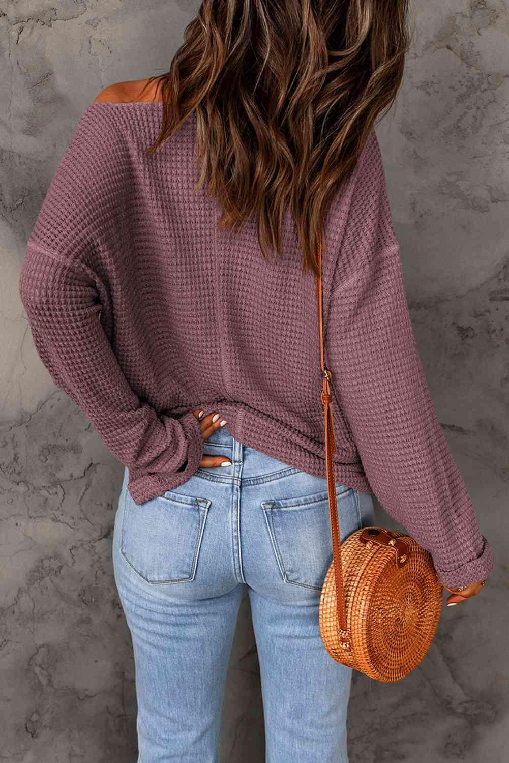 a woman wearing a purple sweater and jeans