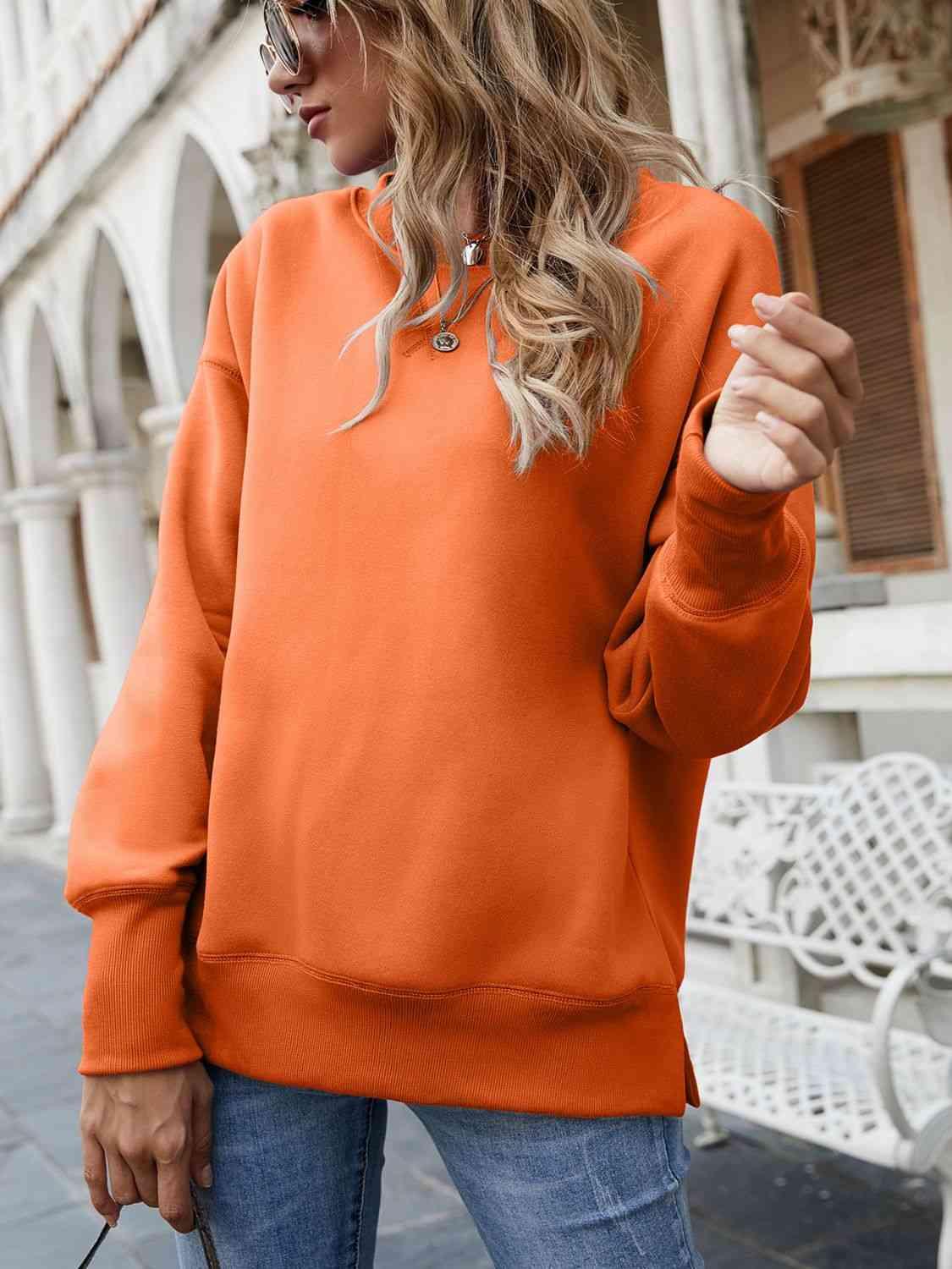 a woman wearing an orange sweatshirt and jeans
