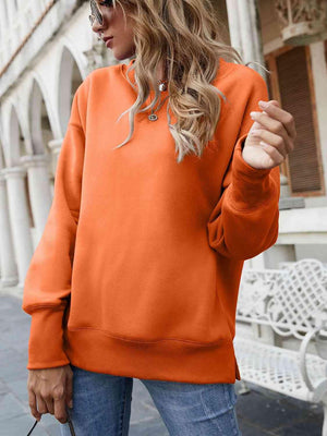 a woman wearing an orange sweatshirt and jeans