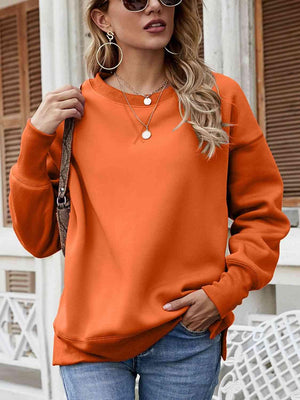 a woman wearing an orange sweatshirt and jeans