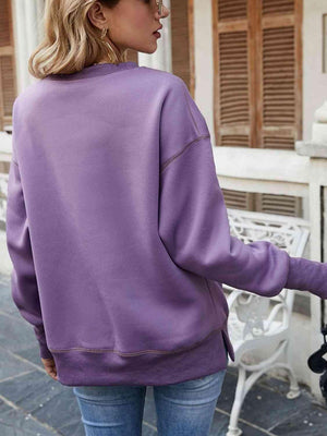 a woman wearing a purple sweatshirt and jeans