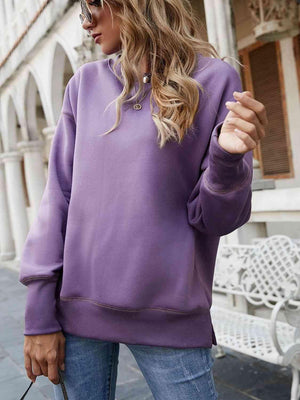 a woman wearing a purple sweatshirt and jeans
