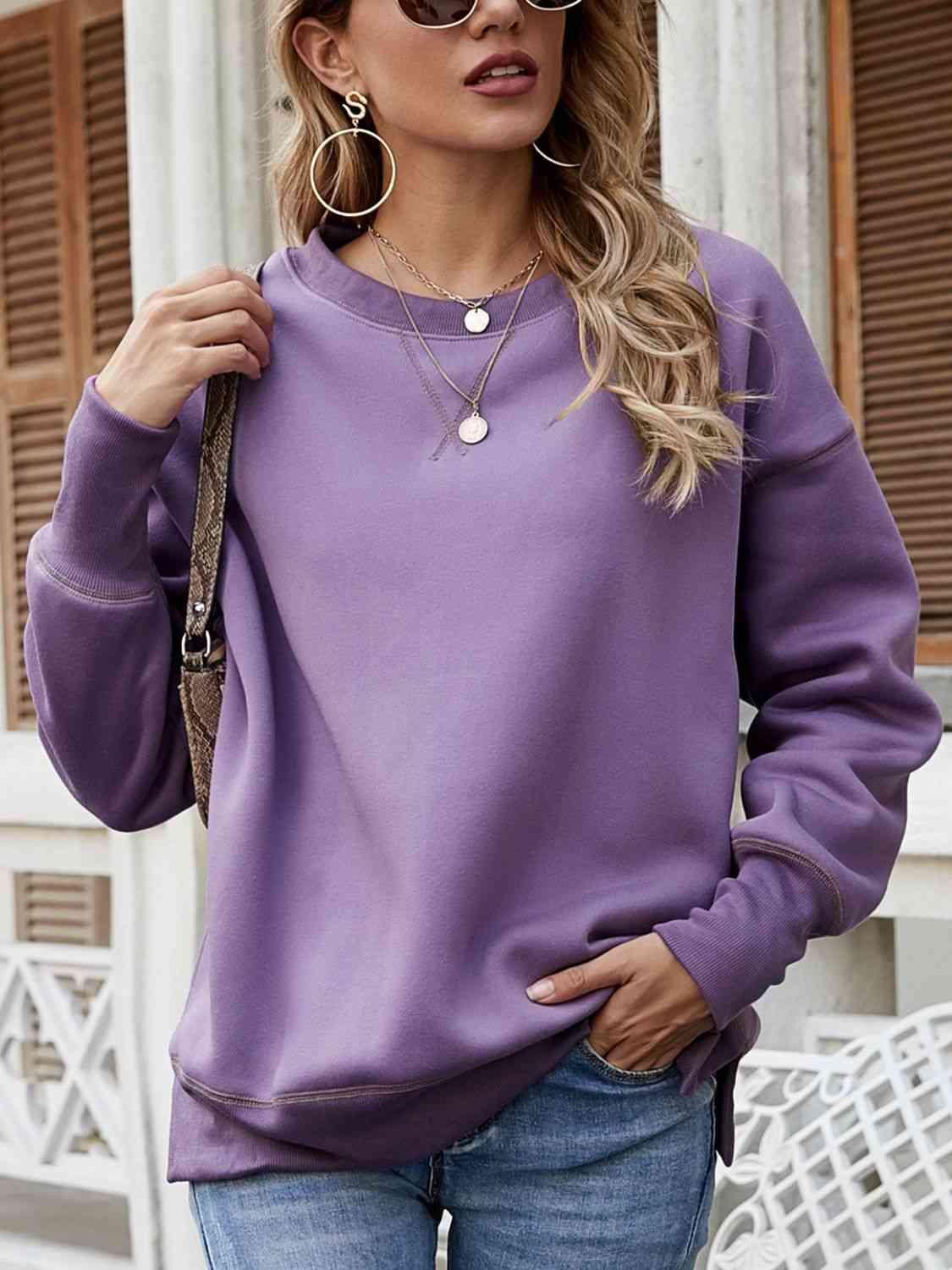 a woman wearing a purple sweatshirt and jeans