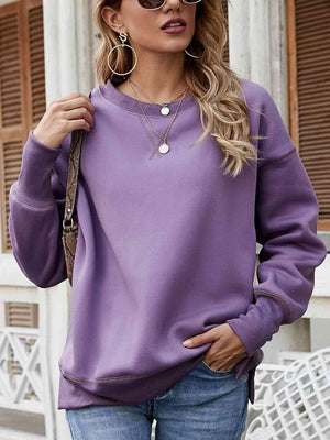 a woman wearing a purple sweatshirt and jeans