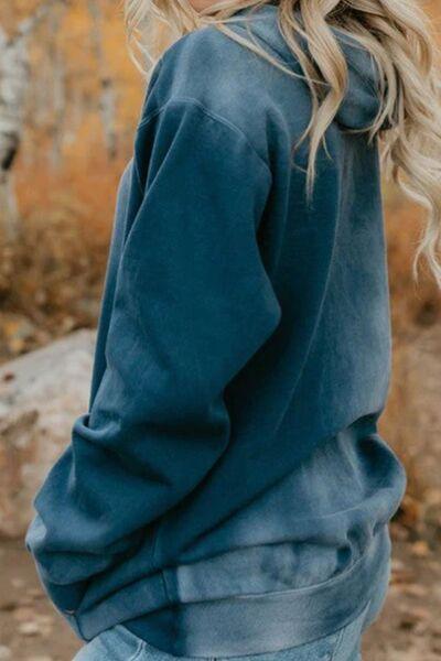 a blonde woman wearing a blue sweatshirt and jeans
