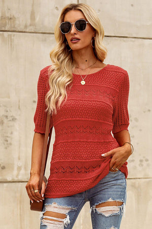 a woman wearing a red sweater and ripped jeans