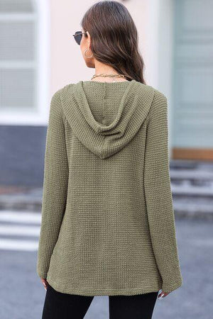 a woman wearing a green sweater and black pants