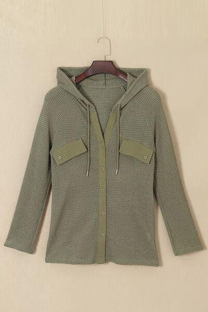 a green cardigan sweater hanging on a hanger