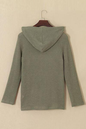 a green sweater hanging on a wall