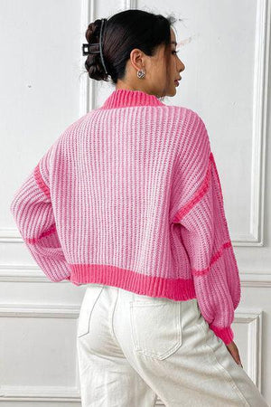 a woman wearing a pink sweater and white pants