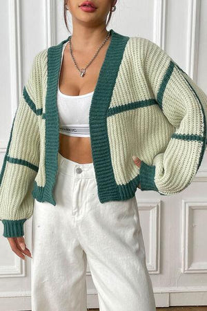 a woman wearing white pants and a green cardigan sweater