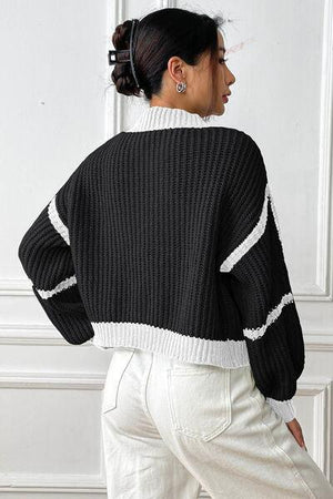 a woman wearing a black and white sweater and white pants