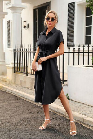 a woman in a black dress is walking down the street