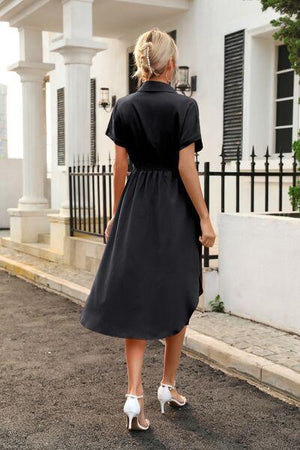 a woman in a black dress is walking down the street