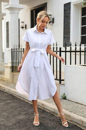 a woman in a white dress is walking down the street