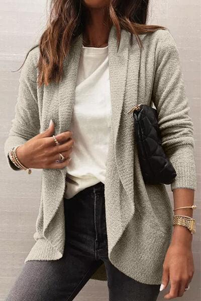 a woman wearing a white top and a gray cardigan