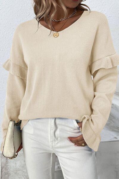 a woman wearing a beige sweater and white jeans