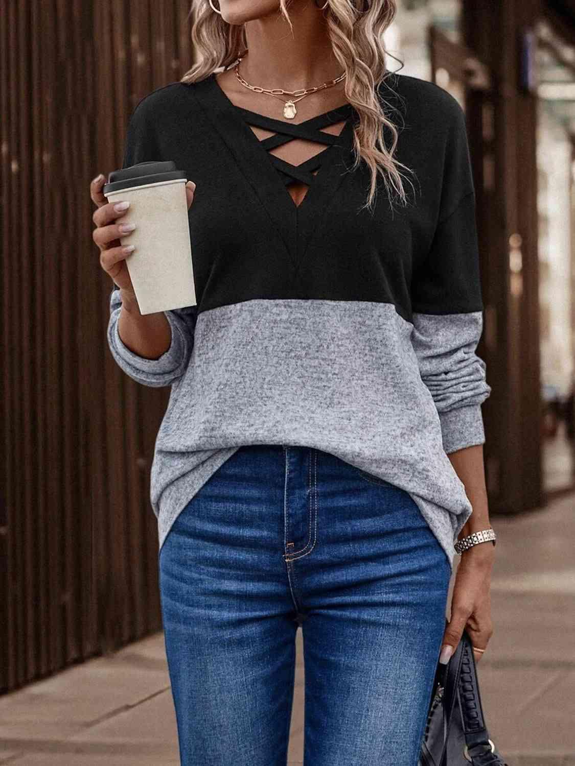 a woman wearing a black and grey sweater and jeans