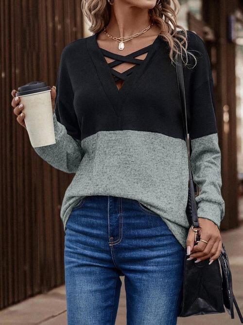 a woman wearing a black and grey sweater and jeans