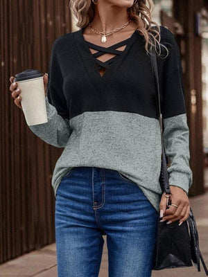 a woman wearing a black and grey sweater and jeans