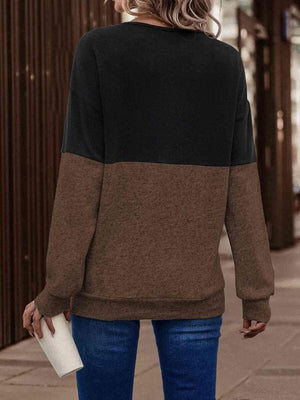a woman standing on a sidewalk wearing a brown and black sweater