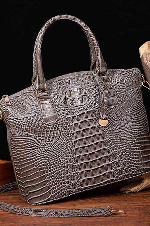a crocodile skin purse sitting on top of a wooden table