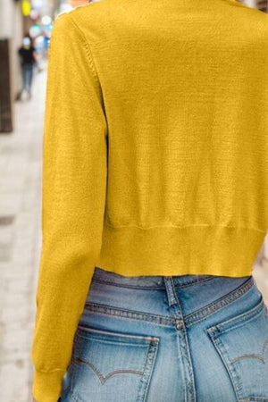 the back of a woman's yellow sweater on a city street