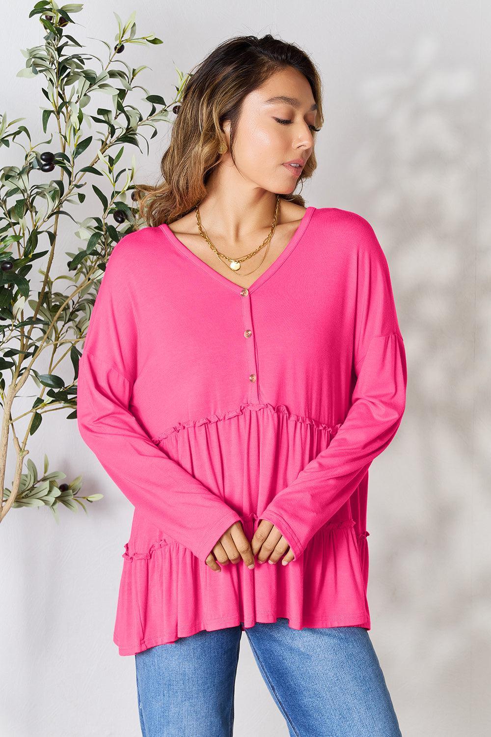 a woman standing in front of a plant wearing a pink top