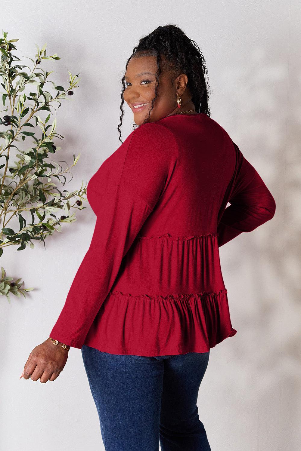 a woman in a red top standing next to a plant