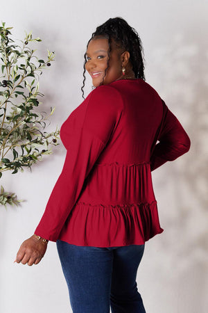 a woman in a red top standing next to a plant