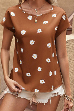 a woman wearing a brown top with white flowers on it