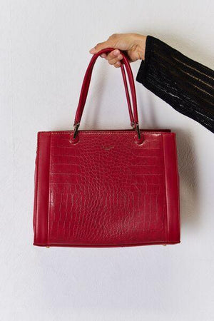 a woman's hand holding a red purse