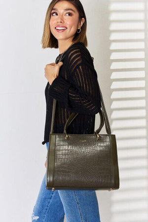 a woman carrying a green handbag while standing in front of a white wall