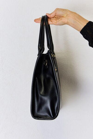 a person holding a black purse in their hand