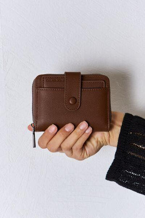 a person holding a brown wallet in their hand